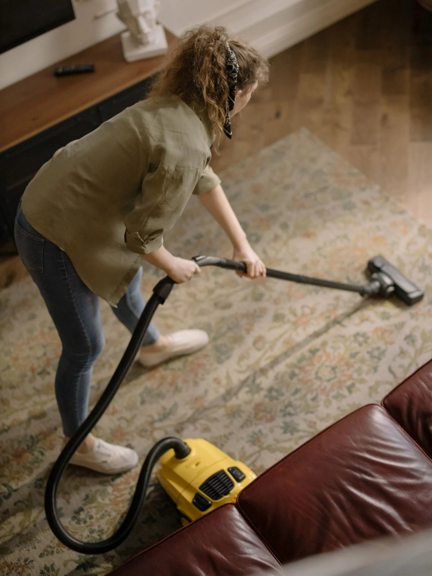 Woman vacuuming a patterned rug in a living room. — illustrative photograph.